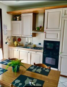 a kitchen with white cabinets and a wooden table at Appartamento Elena in Garda