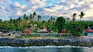 um resort com palmeiras e um corpo de água em Pebble & Fins Bali Dive Resort em Tulamben
