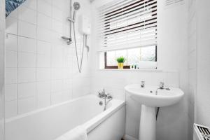 un bagno bianco con lavandino, vasca e lavandino di Luxury 3 Bed House - Garden - Parking - Netflix - Wifi 