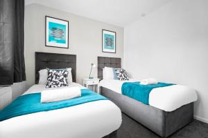 2 letti in una camera con pareti bianche di Luxury 3 Bed House - Garden - Parking - Netflix - Wifi 