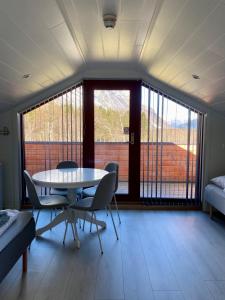 オンダルスネスにあるTrollstigen Camping and Gjestegårdのテーブルと椅子、大きな窓が備わる客室です。