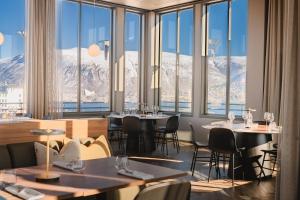 ein Restaurant mit Tischen, Stühlen und Bergen im Hintergrund in der Unterkunft Enter St Elisabeth Suites & Spa in Tromsø