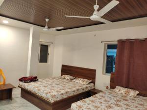 a bedroom with two beds and a ceiling fan at Hotel shree Sidhi vinayak in Ujjain