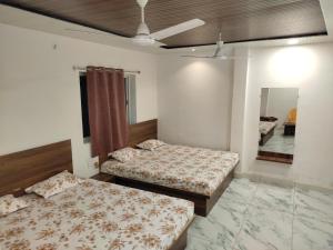 Hotel shree Sidhi vinayak في اوجاين: غرفة نوم بسريرين ومروحة سقف