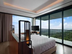 a bedroom with a bed and large glass windows at Royal Tulip Gunung Geulis Resort and Golf in Bogor