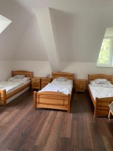 three beds in a room with wooden floors at Penzion Ameryka in Jablunkov