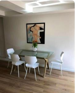 une salle à manger avec une table en verre et des chaises blanches dans l'établissement Terrazzo, à Bastia