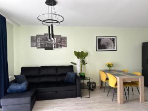 - un salon avec un canapé noir et une table dans l'établissement Apartament NATURA z widokiem na jezioro, à Iława