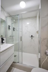a white bathroom with a shower and a sink at Appartement Paisible Climatisé in Malakoff