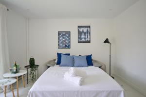 a bedroom with a large white bed with blue pillows at Appartement Paisible Climatisé in Malakoff