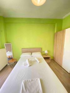 a bedroom with a large white bed with green walls at Olymp Family Apartments Katerini in Katerini