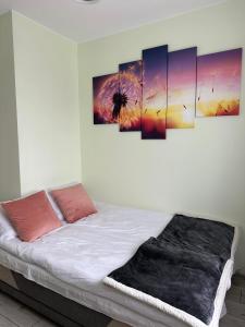 Pokój z łóżkiem z czterema obrazami na ścianie w obiekcie Apartament NATURA z widokiem na jezioro w Iławie