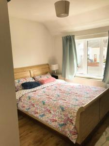 1 dormitorio con 1 cama con edredón de flores y ventana en Spacious 3 bed townhouse in Dublin 12, en Dublín