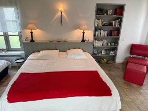 a bedroom with a large bed and a red chair at Ma Chambre d'Amis in Saint-Clément-des-Baleines