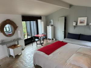 sypialnia z łóżkiem, stołem i lustrem w obiekcie Ma Chambre d'Amis w mieście Saint-Clément-des-Baleines
