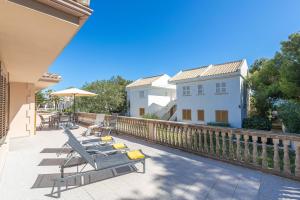 un patio con 2 tumbonas y una sombrilla en Villa LA CANTA, Muro Beach, Alcudia, en Muro