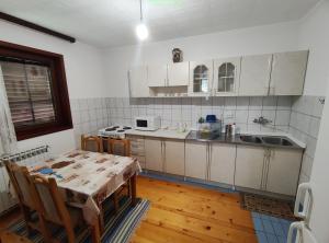 une cuisine avec des placards blancs et une table avec des chaises dans l'établissement Vila FH, à Ilijaš