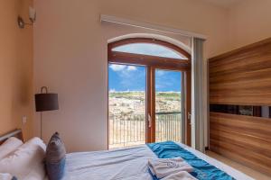 um quarto com uma cama e uma grande janela em Harbour Views Gozitan Villa Shared Pool - Happy Rentals em Mġarr