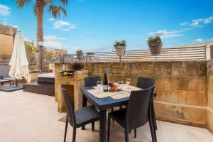 einen Tisch mit Stühlen und eine Flasche Wein auf einer Terrasse in der Unterkunft Harbour Views Gozitan Villa Shared Pool - Happy Rentals in Mġarr
