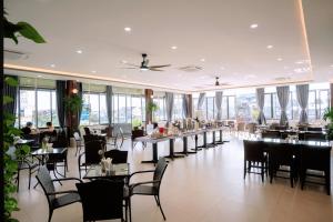 a dining room with tables and chairs and windows at Song Tien Hotel in Mỹ Tho