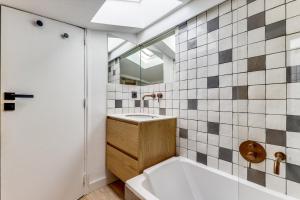 uma casa de banho com uma banheira, um lavatório e um espelho. em L'architecte - Design & Luxueux em Paris