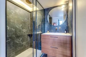 uma casa de banho com um chuveiro, um lavatório e um espelho. em L'architecte - Design & Luxueux em Paris