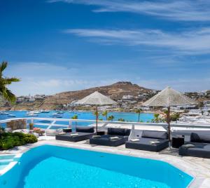 ein Pool mit Liegestühlen und Sonnenschirmen neben einem Resort in der Unterkunft Deliades Hotel in Ornos