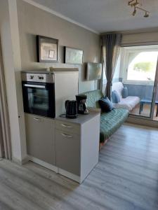 ein Wohnzimmer mit einer Küche und ein Wohnzimmer mit einem Sofa in der Unterkunft Résidence les Floralies 2 - Avenue de Camargue in Le Grau-du-Roi