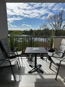 patio ze stołem i krzesłami na balkonie w obiekcie Apartament NATURA z widokiem na jezioro w Iławie
