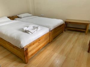 two twin beds in a room with wooden floors at Beli Guest House in Pokhara