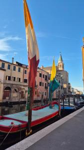 duas bandeiras em postes num barco num canal em Iris House em Chioggia
