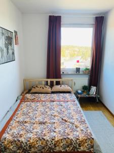 een slaapkamer met een bed en een groot raam bij Cozy room in a shared apartment close to nature in Göteborg