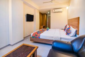 a bedroom with a bed and a couch and a tv at FabHotel Jansi Deluxe Gandhipuram in Coimbatore