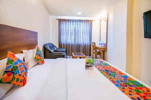Habitación de hotel con cama grande con almohadas coloridas en FabHotel Jansi Deluxe Gandhipuram, en Coimbatore