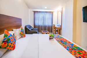 a hotel room with a large bed with colorful pillows at FabHotel Jansi Deluxe Gandhipuram in Coimbatore