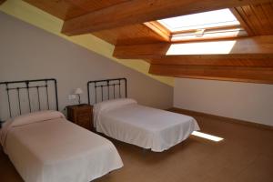 een zolderkamer met 2 bedden en een dakraam bij Albergue Internacional in Sarria