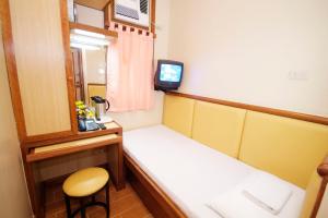 um pequeno quarto com uma cama e uma televisão em Kabayan Hotel Pasay em Manila
