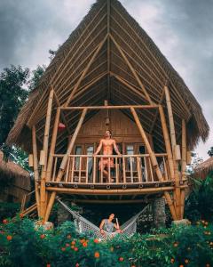 a man and a woman in front of a bamboo house at Penida Bambu Green in Nusa Penida