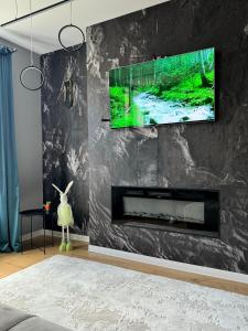 ein Wohnzimmer mit einem an der Wand hängenden TV in der Unterkunft LV Luxury Apart - One minute away from train station in Predeal