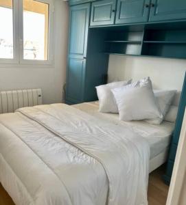 un lit avec des draps blancs et des oreillers dans une chambre dans l'établissement Les Rameaux, superbe appartement vue mer, Wimereux, à Wimereux