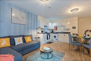 a living room with a blue couch and a kitchen at 247 Serviced Accommodation in Telford 2 BR Apartment in Telford