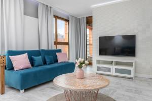 a living room with a blue couch and a tv at Modern Apartment in Gdańsk Center Near the River with Parking by Renters in Gdańsk