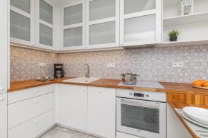 a white kitchen with white cabinets and a sink at Modern Apartment in Gdańsk Center Near the River with Parking by Renters in Gdańsk
