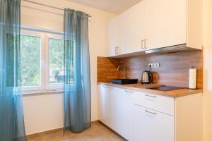 a kitchen with white cabinets and a window at Apartment Wish - two bedrooms with 2 AC renewed in Pag