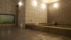 越谷市にあるNatural hot spring with sauna HOTEL GLAN Y's KOSHIGAYAの大きな壁掛けテレビが備わる広い客室です。