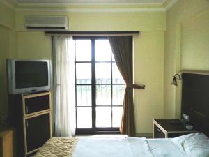 Schlafzimmer mit einem Fenster, einem Bett und einem TV in der Unterkunft Hamle Hotel in Akyaka