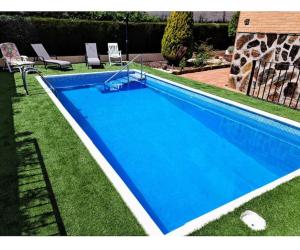 een blauw zwembad in het gras met twee stoelen bij Casa rural Brisa de Toledo in Cobisa