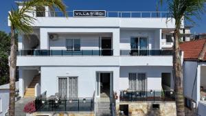 a white building with palm trees in front of it at Vila Irdi in Ksamil