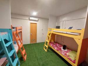 a room with two bunk beds and green carpet at Sun Valley Hostel in El Nido