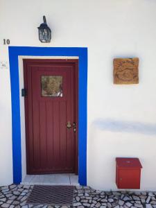 czerwone drzwi na boku białego budynku w obiekcie 10 da Muralha w mieście Estremoz